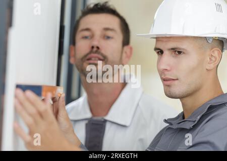 mur à deux personnes maintenant le niveau à bulle sur le chantier de construction Banque D'Images