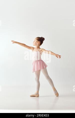 Portrait de petite adorable ballerine danseuse d'âge préscolaire en rose tutu robe de ballet blanc legging debout posant sur fond blanc. Banque D'Images