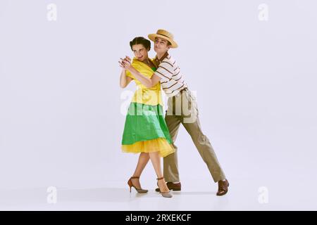 Joyeux et talentueux jeune couple, homme et femme dans des vêtements élégants dansant isolé sur fond de studio blanc Banque D'Images