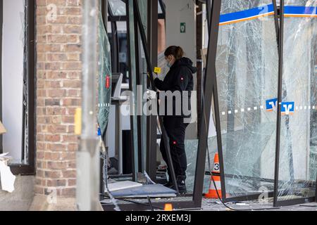 Erfstadt, Allemagne. 25 septembre 2023. Une femme officier de médecine légale obtient des preuves à l'entrée d'une succursale bancaire. Lundi matin, des inconnus ont fait sauter un guichet automatique dans une succursale bancaire à Erftstadt. Crédit : Thomas Banneyer/dpa/Alamy Live News Banque D'Images