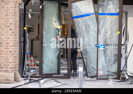 Erfstadt, Allemagne. 25 septembre 2023. Une femme officier de médecine légale obtient des preuves à l'entrée d'une succursale bancaire. Lundi matin, des inconnus ont fait sauter un guichet automatique dans une succursale bancaire à Erftstadt. Crédit : Thomas Banneyer/dpa/Alamy Live News Banque D'Images