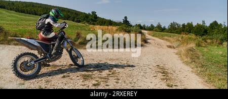 Un pilote de motocross professionnel qui roule de manière exaltante sur une piste forestière hors route dangereuse sur sa moto. Banque D'Images