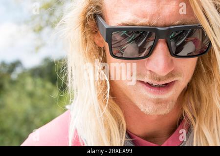 Portrait d'homme avec de longs cheveux portant des lunettes de soleil Banque D'Images