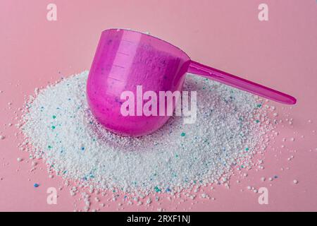 Poudre à laver dans la cuillère en plastique sur fond rose vue de dessus. Photo de haute qualité Banque D'Images