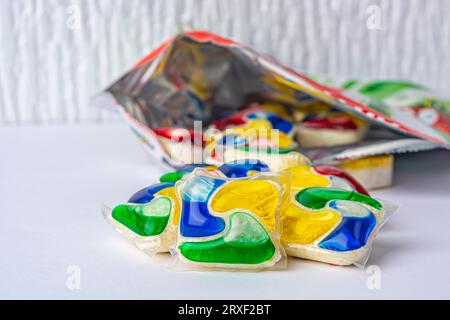 capsules pour lave-vaisselle devant un emballage ouvert sur fond blanc. Photo de haute qualité Banque D'Images