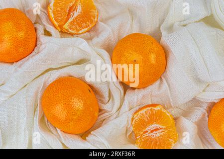 Les mandarines fraîches sont situées sur un fond de tissu blanc Banque D'Images