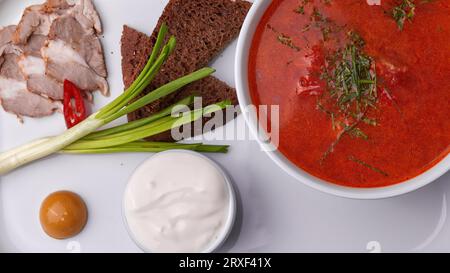 Borsch ukrainien avec crème sure, oignons et bacon sur une assiette blanche Banque D'Images