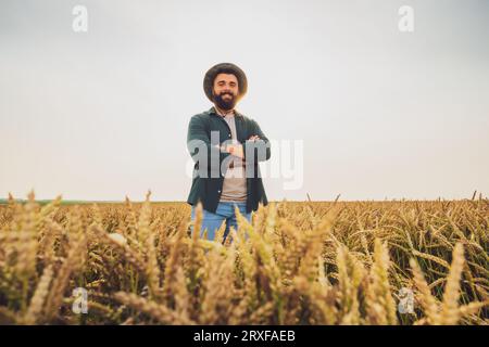 Portrait de fermier qui cultive du blé. Il est satisfait de la bonne progression des plantes. Occupation agricole. Banque D'Images