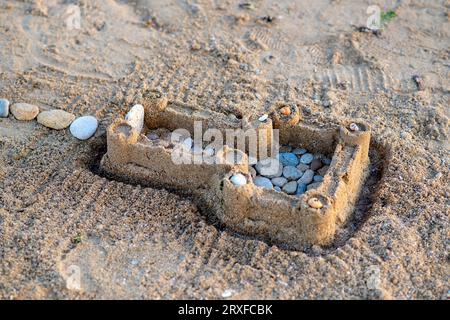 Château de sable pour enfants sur la plage. Vacances d'été. Pierres de mer et coquillages dans le sable Banque D'Images