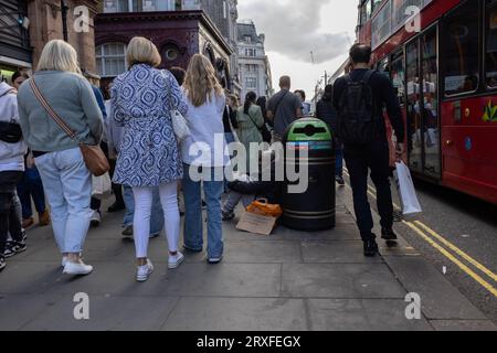 Les piétons sur une rue animée d'Oxford Circus passent devant un homme sans abri presque invisible parmi les acheteurs, Londres, Royaume-Uni Banque D'Images