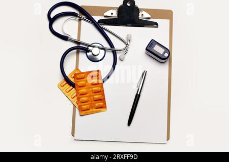 Appareil portable de mesure du pouls cardiaque à doigt, stéthoscope et blister de pilule médicale sur un presse-papiers Banque D'Images