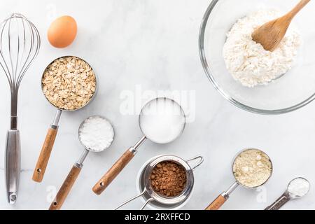 Divers ustensiles de cuisson et ingrédients sur une table en marbre blanc. Banque D'Images