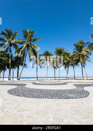 Célèbre Boardwalk sur la plage de Copacabana et cocotiers avec ciel bleu à Rio de Janeiro Brésil. Banque D'Images