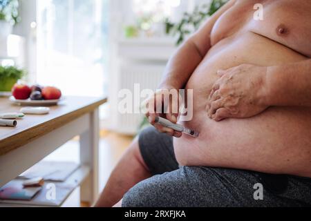 Gros plan d'un homme diabétique utilisant un glucomètre continu pour vérifier le taux de sucre dans le sang. Banque D'Images