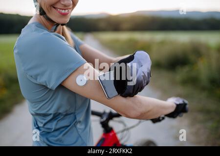 Cycliste diabétique connectant un moniteur de glycémie continu à son smartphone pour surveiller son taux de sucre dans le sang en temps réel. Banque D'Images