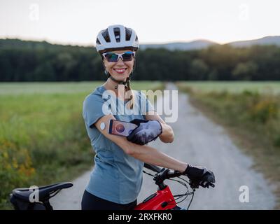 Cycliste diabétique connectant un moniteur de glycémie continu à son smartphone pour surveiller son taux de sucre dans le sang en temps réel. Banque D'Images