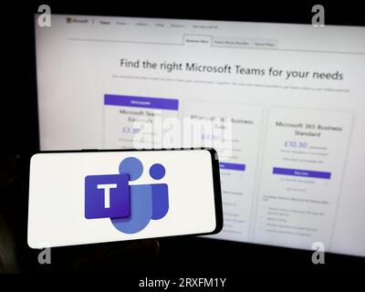 Personne tenant le téléphone mobile avec le logo de la plate-forme de communication d'entreprise Microsoft Teams sur l'écran en face de la page Web. Concentrez-vous sur l'affichage du téléphone. Banque D'Images