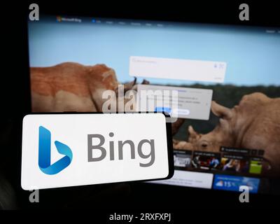 Personne tenant le téléphone mobile avec le logo du moteur de recherche Web Microsoft Bing sur l'écran en face de la page Web d'entreprise. Concentrez-vous sur l'affichage du téléphone. Banque D'Images