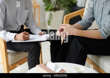 Image recadrée du psychologue remplissant le formulaire lorsqu'il parle au patient Banque D'Images