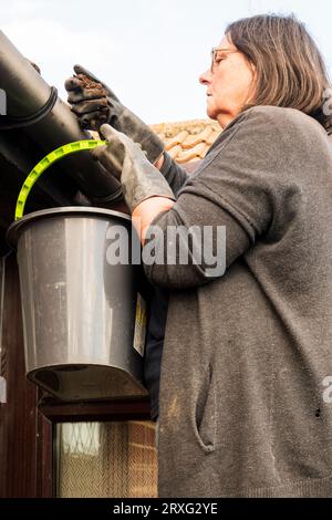 Femme débarrassant la mousse du caniveau. Banque D'Images