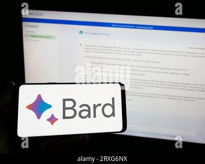 Personne tenant smartphone avec logo de chatbot génératif ai Google Bard sur l'écran en face du site Web. Concentrez-vous sur l'affichage du téléphone. Banque D'Images