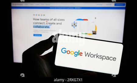Personne tenant le smartphone avec le logo du logiciel d'application d'entreprise Google Workspace sur l'écran en face du site Web. Concentrez-vous sur l'affichage du téléphone. Banque D'Images