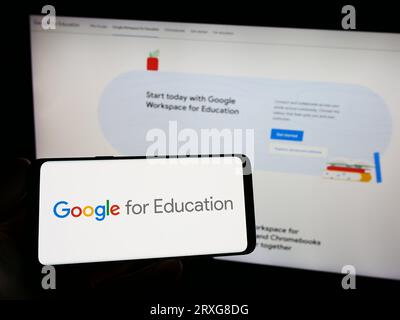 Personne tenant le smartphone avec le logo du produit logiciel Google pour l'éducation sur l'écran en face du site Web. Concentrez-vous sur l'affichage du téléphone. Banque D'Images