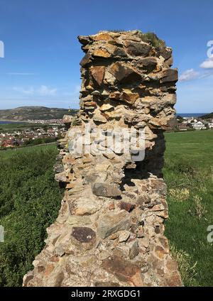 Vue des murs en ruine de l'entrée du château de Deganwy, pays de Galles, qui surmontent une falaise de tuf rhyolitique ordovicien regardant vers Llandudno au loin Banque D'Images