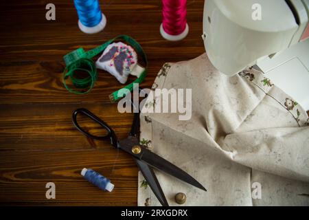un ensemble d'outils et de fils pour coudre des vêtements, sur fond de bois. Banque D'Images