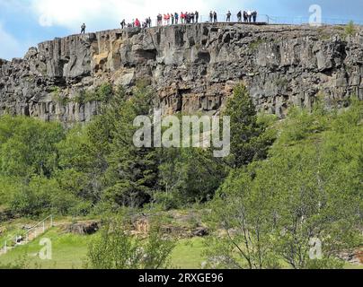 Touristes sur un rocher dans le parc national de Thingvellir dans le sud-ouest de l'Islande. Le parc national est un site du patrimoine mondial de l'UNESCO. Région de la capitale Banque D'Images