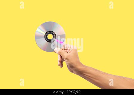 Main mâle noire tenant un disque cd isolé sur fond jaune Banque D'Images