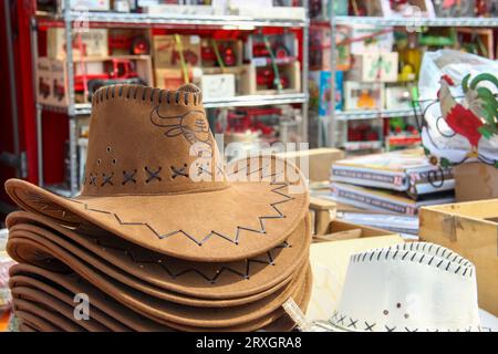 Une pile de chapeaux de cow-boy marron et blanc assis sur une table dans un magasin.. Le chapeau de cow-boy est une représentation du style ouest-américain. Le chapeau a une illustration d'un taureau. Banque D'Images