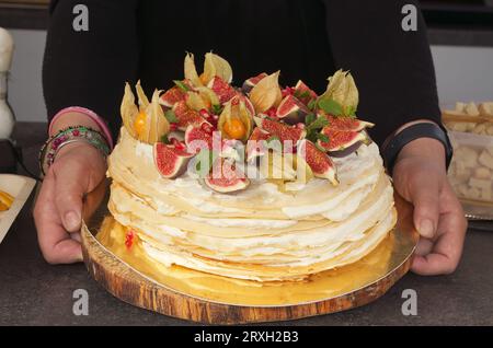 Corps de section médiane du vendeur montrant le gâteau de crêpe joliment décoré avec des figues fraîches, des cerises péruviennes et des graines de grenade. Banque D'Images