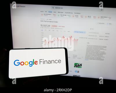 Personne tenant smartphone avec logo de la plate-forme d'information financière Google Finance sur l'écran en face du site Web. Concentrez-vous sur l'affichage du téléphone. Banque D'Images