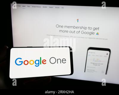 Personne tenant smartphone avec logo du service d'abonnement logiciel Google One sur l'écran en face du site Web. Concentrez-vous sur l'affichage du téléphone. Banque D'Images