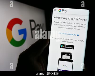 Personne tenant smartphone avec page Web du service de paiement mobile Google Pay sur l'écran en face du logo. Concentrez-vous sur le centre de l'écran du téléphone. Banque D'Images