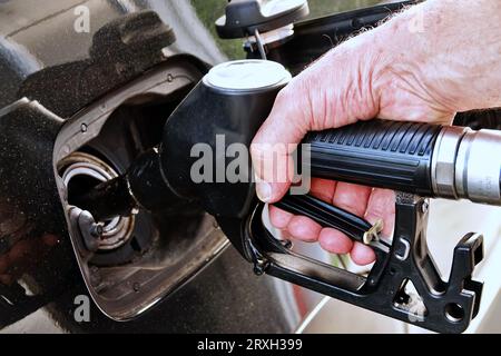 Ravitailler la voiture, la main d'un homme remplit le carburant diesel à la station-service et la pompe à essence remplit la buse de carburant dans le réservoir de la voiture. Banque D'Images