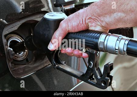 Ravitailler la voiture, la main d'un homme remplit le carburant diesel à la station-service et la pompe à essence remplit la buse de carburant dans le réservoir de la voiture. Banque D'Images