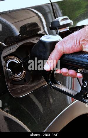 Ravitailler la voiture, la main d'un homme remplit le carburant diesel à la station-service et la pompe à essence remplit la buse de carburant dans le réservoir de la voiture. Banque D'Images