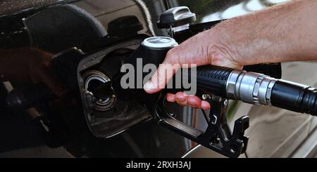 Ravitailler la voiture, la main d'un homme remplit le carburant diesel à la station-service et la pompe à essence remplit la buse de carburant dans le réservoir de la voiture. Banque D'Images