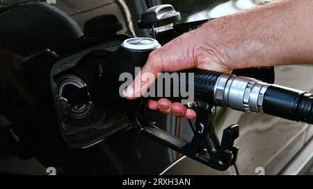 Ravitailler la voiture, la main d'un homme remplit le carburant diesel à la station-service et la pompe à essence remplit la buse de carburant dans le réservoir de la voiture. Banque D'Images