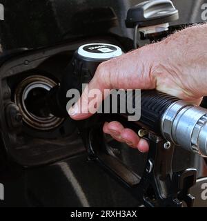 Ravitailler la voiture, la main d'un homme remplit le carburant diesel à la station-service et la pompe à essence remplit la buse de carburant dans le réservoir de la voiture. Banque D'Images