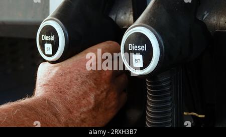 Ravitailler la voiture, la main d'un homme remplit le carburant diesel à la station-service et la pompe à essence remplit la buse de carburant dans le réservoir de la voiture. Banque D'Images