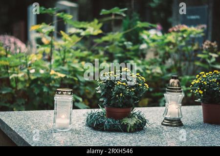 fleurs décoratives, bougies, couronne sur la tombe dans le cimetière Banque D'Images