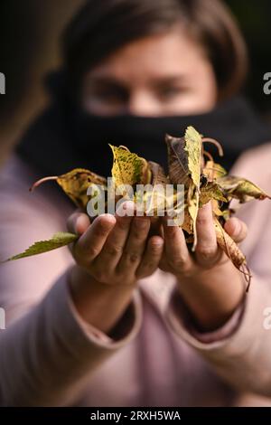 Ottignies Louvain la Neuve, Belgique. 25 septembre 2023. L'illustration montre une femme tenant quelques feuilles fanées au début de la saison d'automne, lundi 25 septembre 2023, à Ottignies/Louvain-la-Neuve. BELGA PHOTO LAURIE DIEFFEMBACQ crédit : Belga News Agency/Alamy Live News Banque D'Images