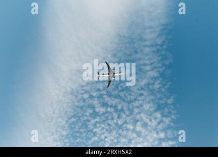 Silhouette d'avion volant dans le ciel bleu avec des nuages blancs. Concept de voyage et de transport - avion de passagers en vol - photo prise d'en bas (g Banque D'Images