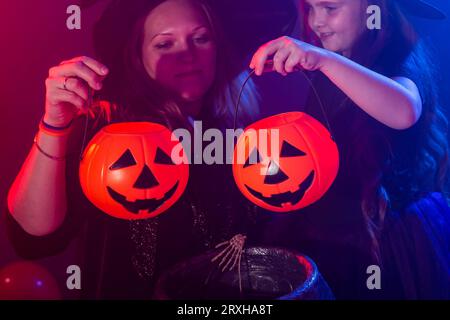 Drôle d'enfant fille et femme dans des costumes de sorcières pour Halloween faisant de la magie avec Jack Lantern gros plan Banque D'Images