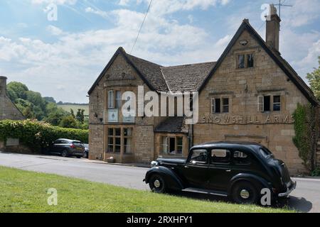 Une voiture noire vintage garée devant les Snowshill Arms, une auberge en pierre de cotswold 15c, par une journée d'été lumineuse. Banque D'Images