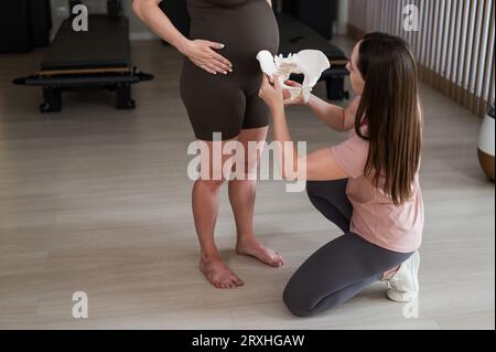 Doula explique le processus d'accouchement sur un échantillon du bassin d'une femme enceinte. Banque D'Images