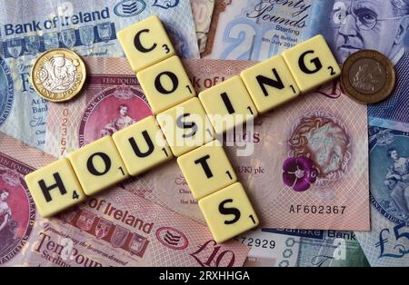Coûts de logement - en mots, des lettres scrabble avec des billets de trésorerie Sterling d'Irlande du Nord - vingt livres, dix livres, cinq livres, livres, livres Banque D'Images